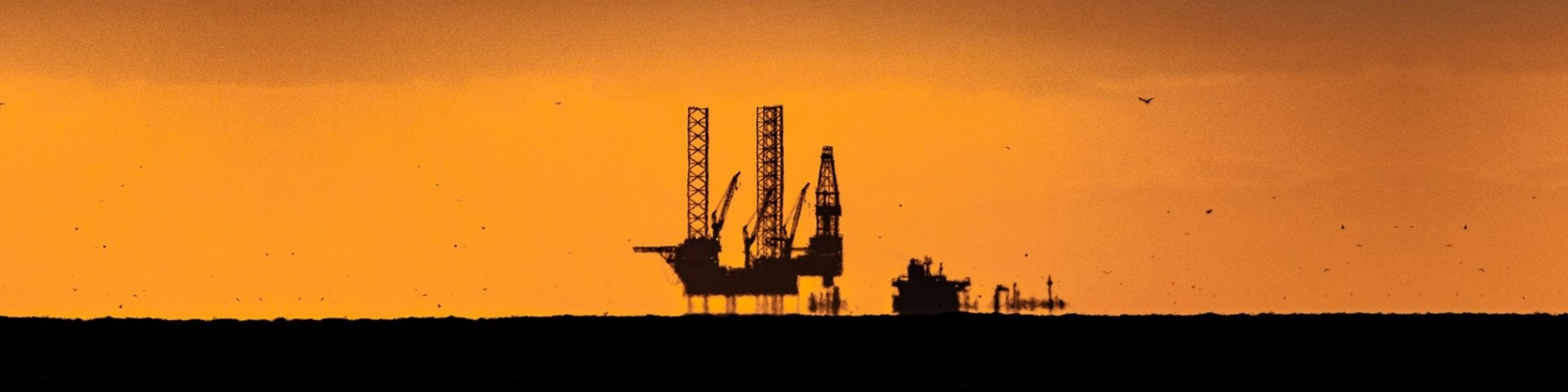 An oil rig in the ocean with the sun setting